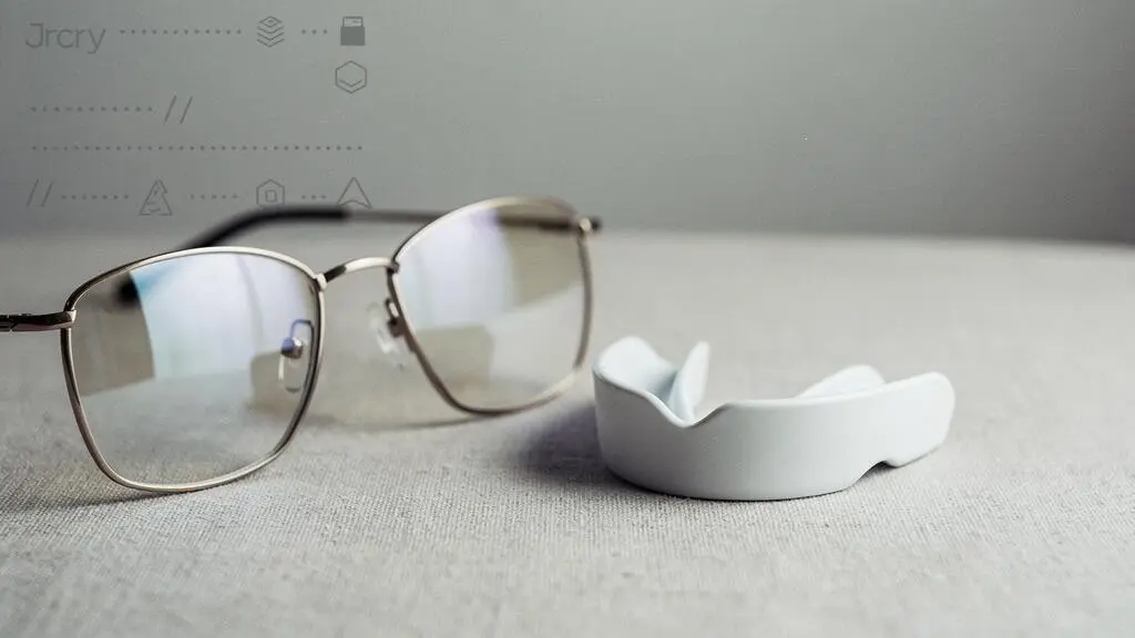 Paire de lunettes et empreinte dentaire abstraite posées avec soin sur une surface neutre, symbolisant l'accès à des soins essentiels sans reste à charge